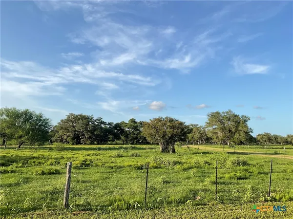 a view of a green field with wooden fence