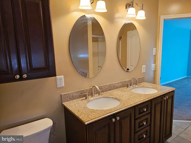a bathroom with a granite countertop double vanity sink and a mirror