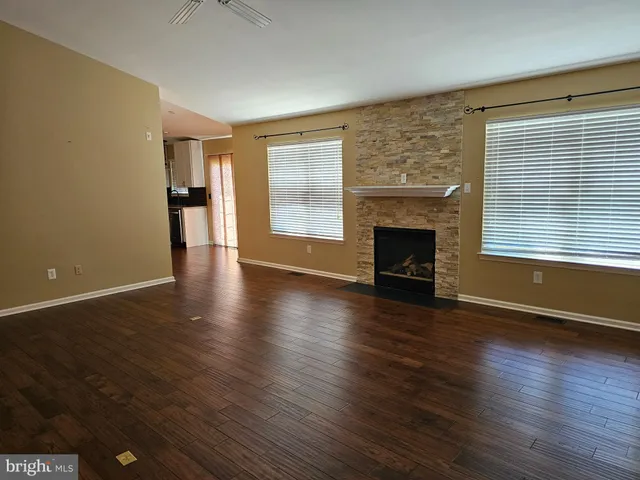 an empty room with wooden floor fireplace and windows