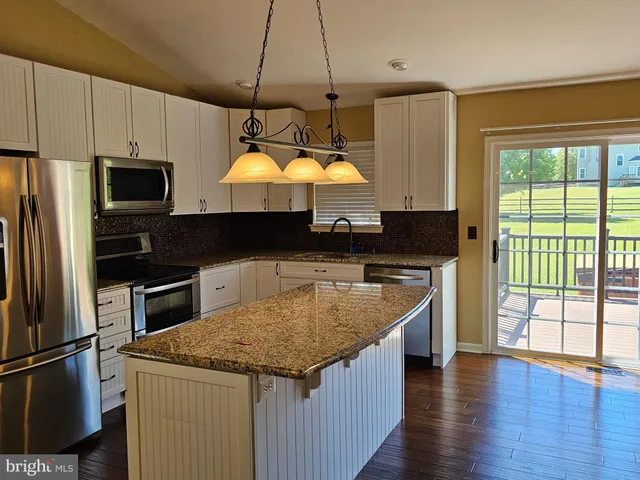 a kitchen with stainless steel appliances granite countertop a sink a stove and a refrigerator