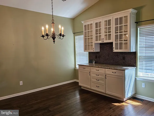 a view of a kitchen with granite countertop cabinets a sink and a chandelier