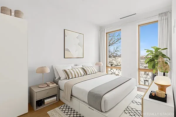 a bedroom with a bed a couch and potted plant next to a window