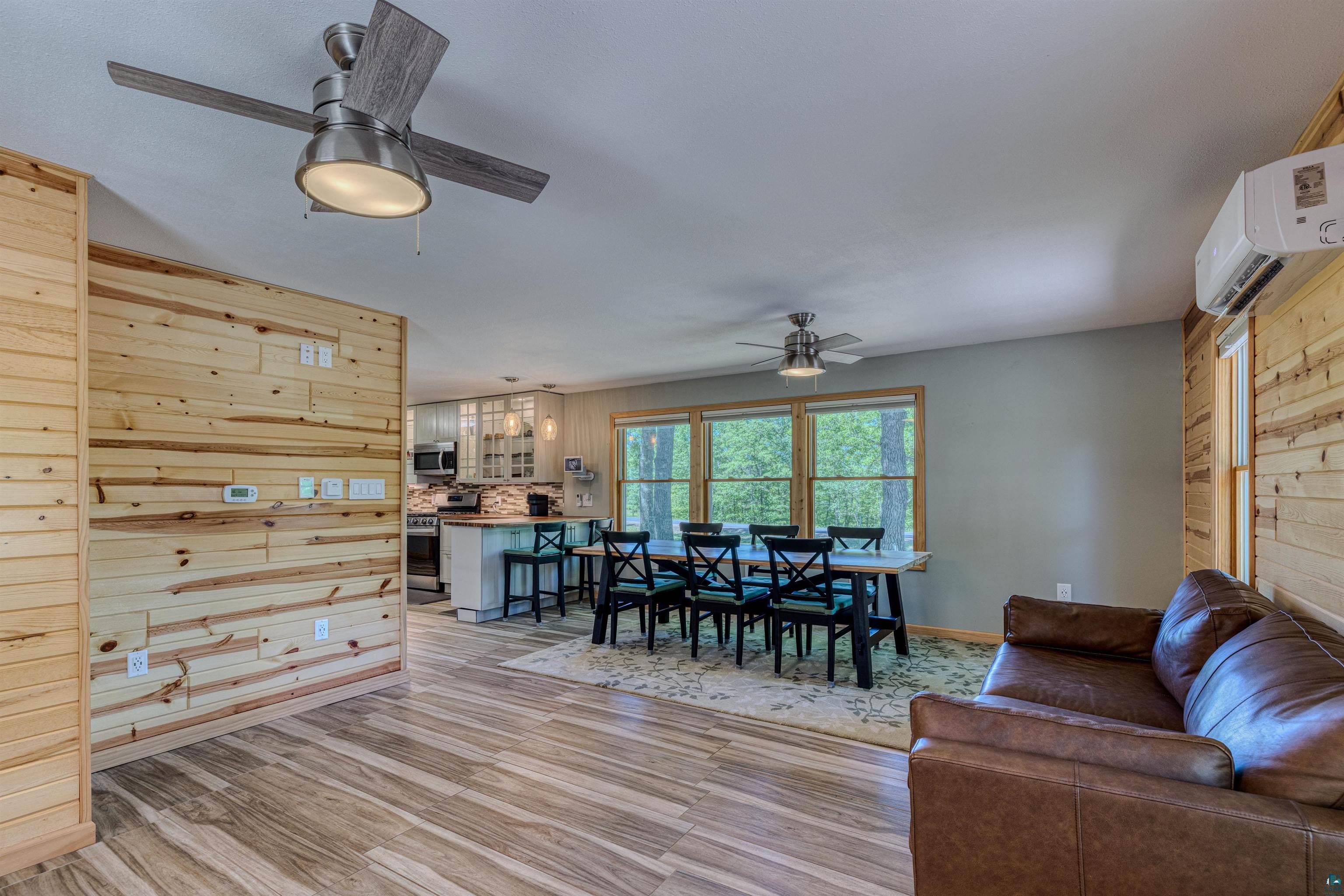66075 Rooster Road Iron River, WI 54847 - Photo 19 of 52 Open-concept living space featuring wood-finish flooring, accent wood paneling, and multiple ceiling fans