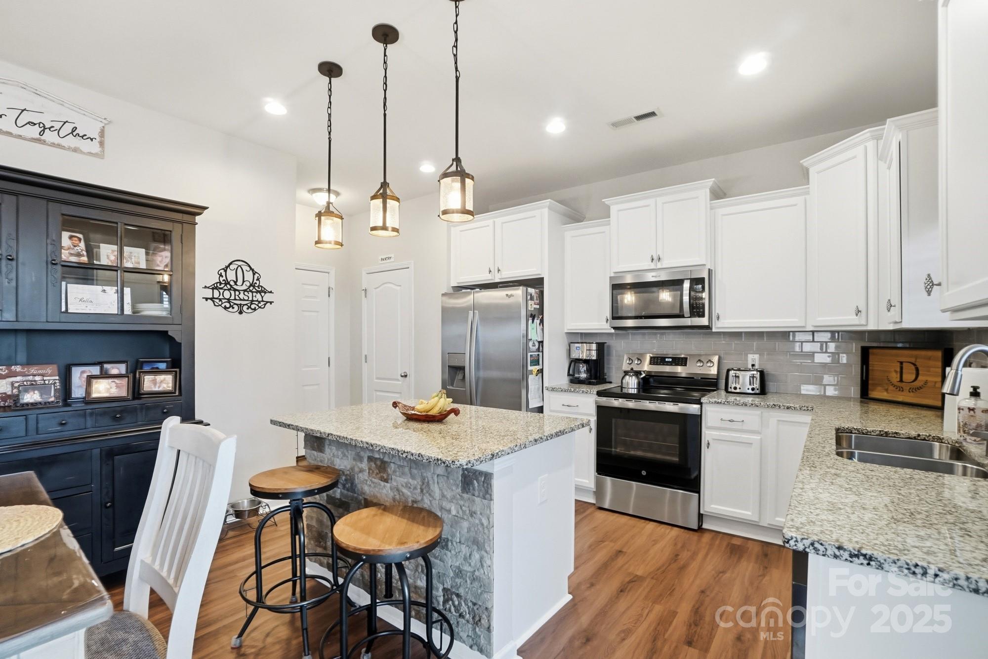5033 Haven Lodge Road Matthews, NC 28104 - Photo 13 of 37 a kitchen with stainless steel appliances granite countertop a stove top oven a refrigerator a sink dishwasher a dining table and chairs with wooden floor