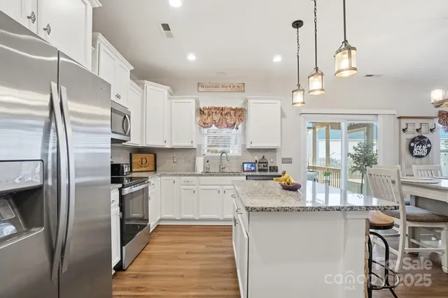 a kitchen with stainless steel appliances granite countertop a refrigerator a stove and white cabinets