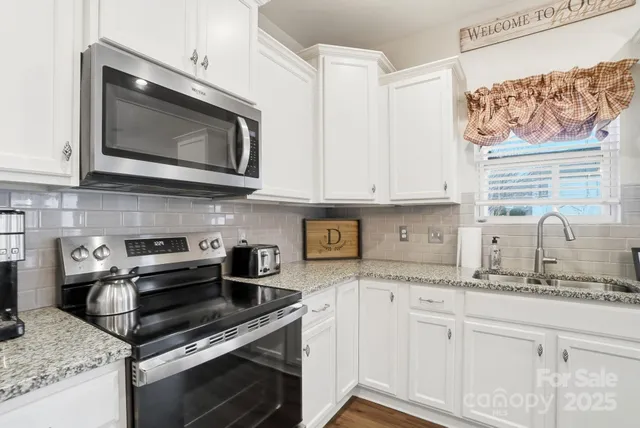 a kitchen with granite countertop white cabinets stainless steel appliances and a sink