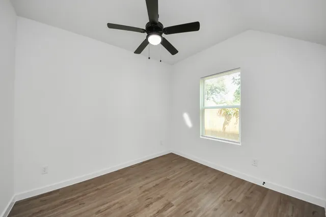 an empty room with a window and a ceiling fan