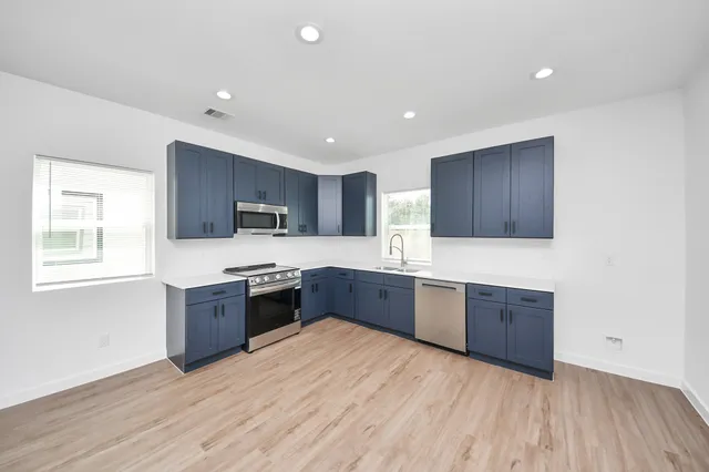 a large kitchen with wooden floors and stainless steel appliances