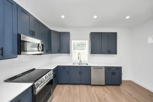 a kitchen with stainless steel appliances granite countertop a stove a sink and a microwave