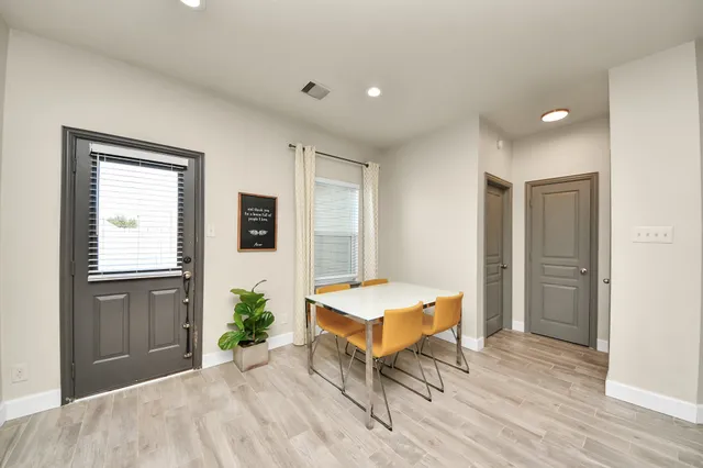 a large white kitchen with kitchen island a refrigerator a stove a sink dishwasher and a dining table with wooden floor