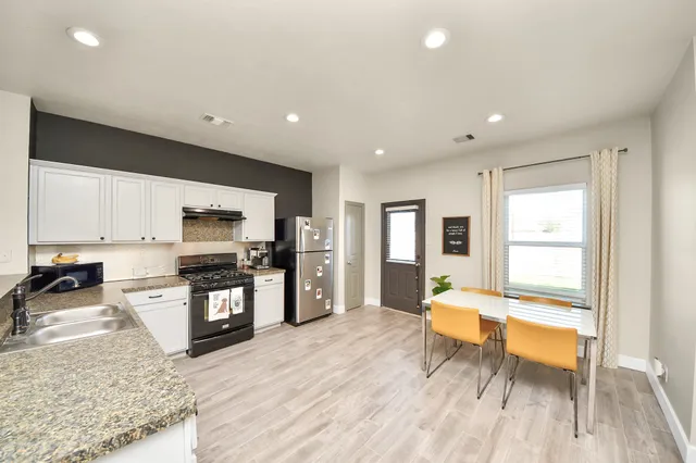 a view of a kitchen with kitchen island a counter top space a sink a window and stainless steel appliances
