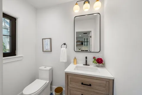 a bathroom with a toilet sink vanity and mirror