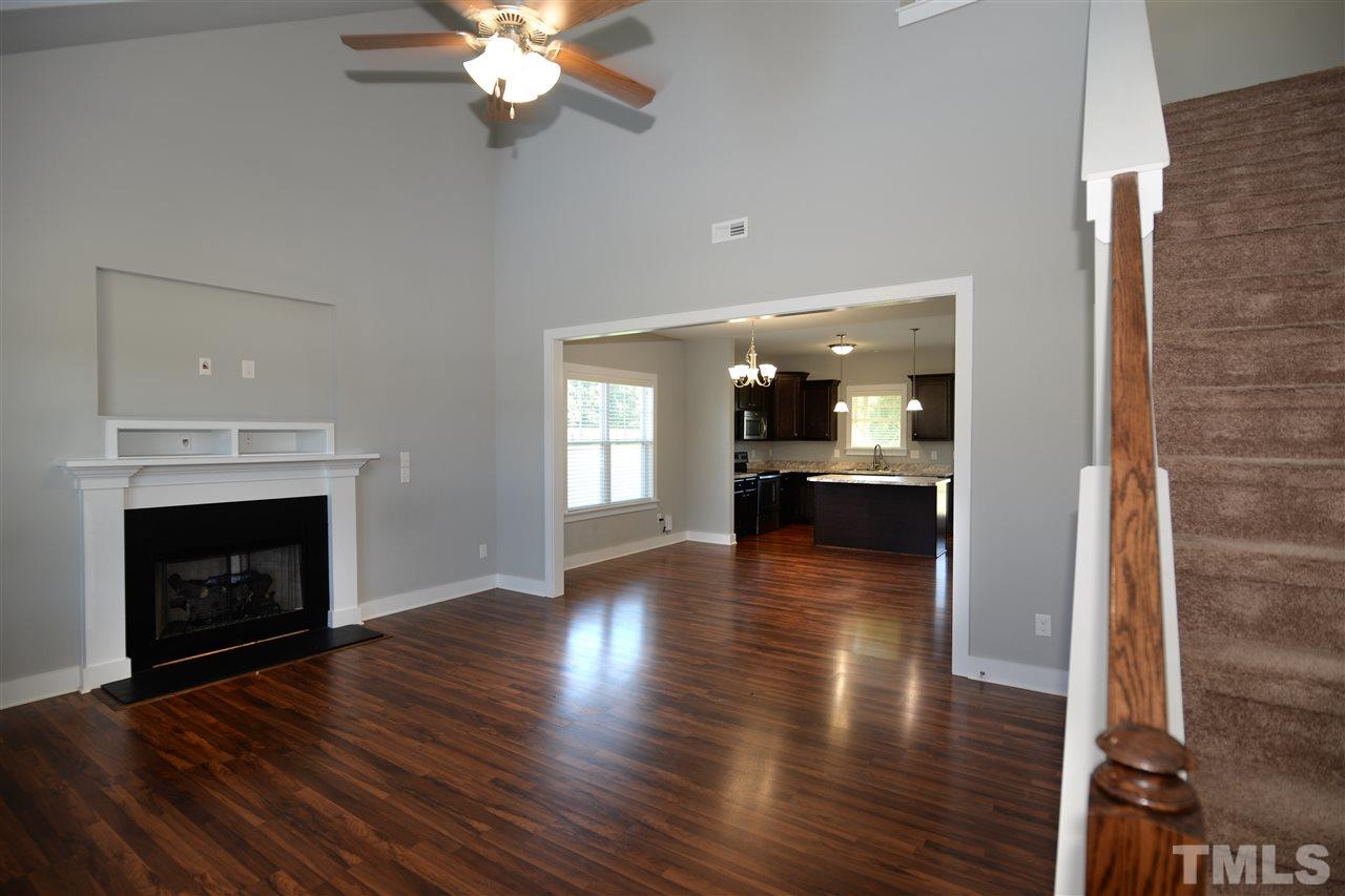 179 Red Wood Road Zebulon, NC 27597 - Photo 5 of 25 a view of a kitchen and an empty room with wooden floor and a fireplace