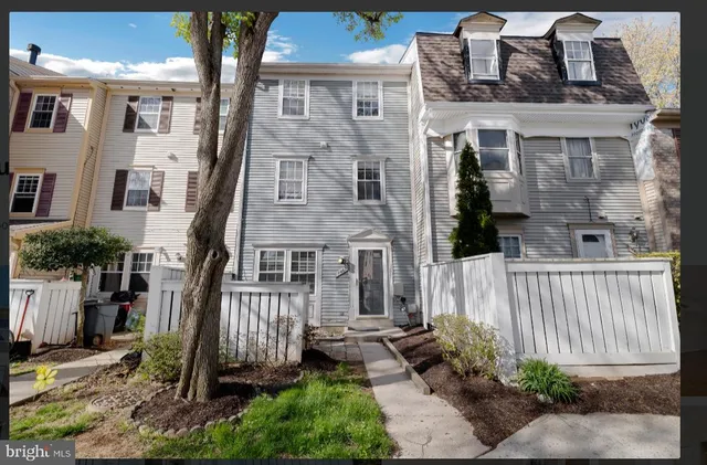 a view of a brick house with many windows plants and large trees