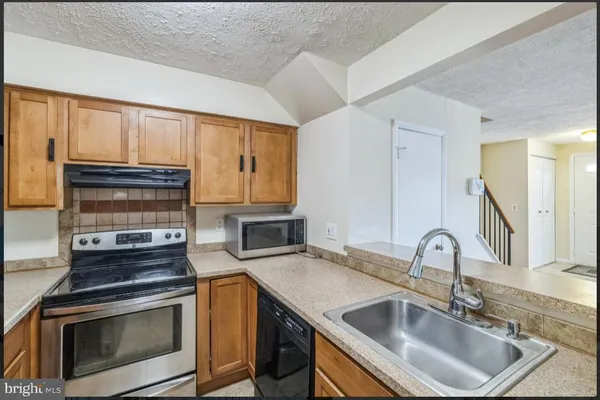 a kitchen with granite countertop a sink stove and cabinets