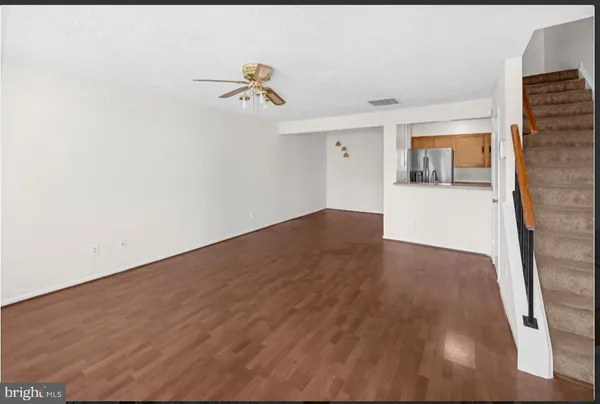 a view of a room with wooden floor and a ceiling fan