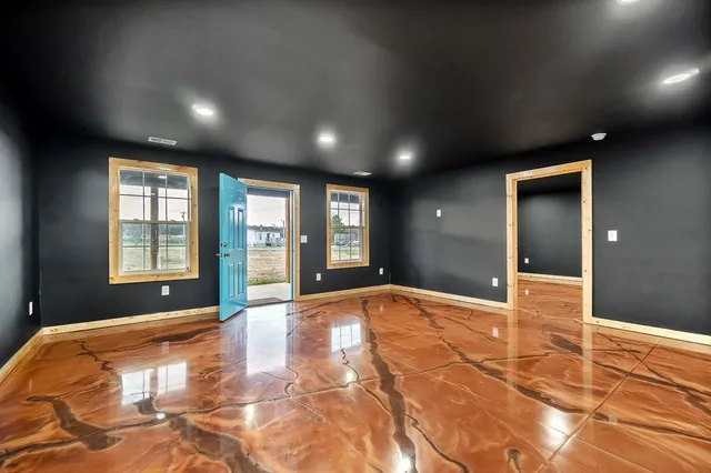 a view of an empty room with window and wooden floor