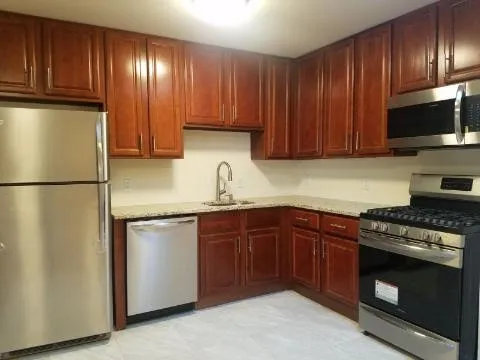a kitchen with granite countertop wooden cabinets stainless steel appliances and a sink