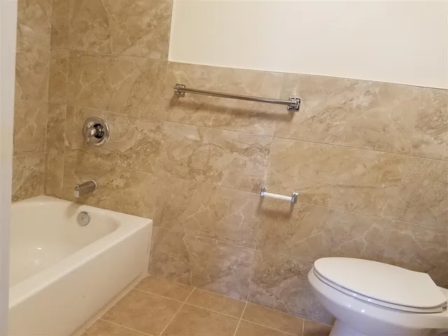 a white toilet sitting next to a bath tub and a shower