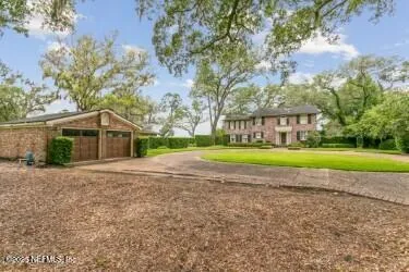 a view of a house with a big yard and large trees