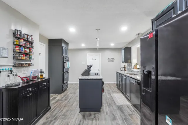 a kitchen with stainless steel appliances kitchen island granite countertop a refrigerator a stove top oven and a sink