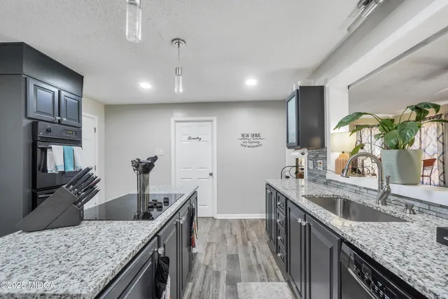 a kitchen with stainless steel appliances granite countertop a sink a stove and a wooden cabinets