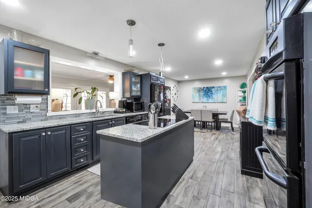 a kitchen with stainless steel appliances granite countertop sink stove top oven and cabinets