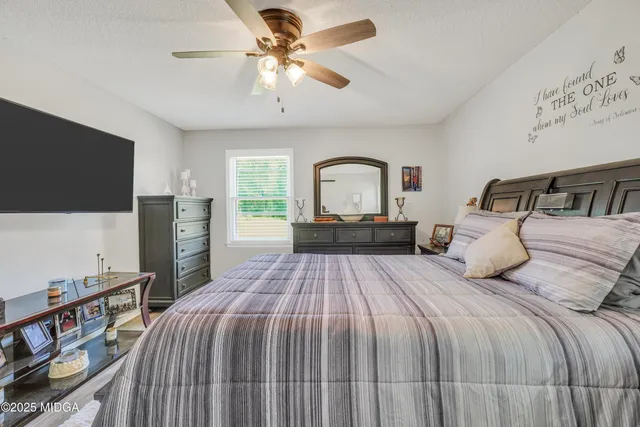 a bedroom with a bed and a flat tv screen on dresser