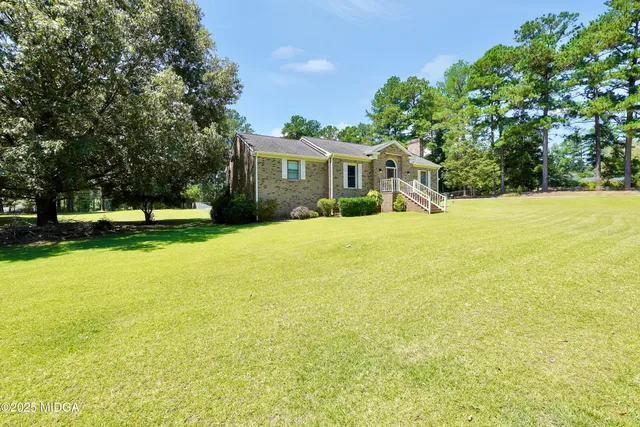 a view of a house with a yard and sitting area