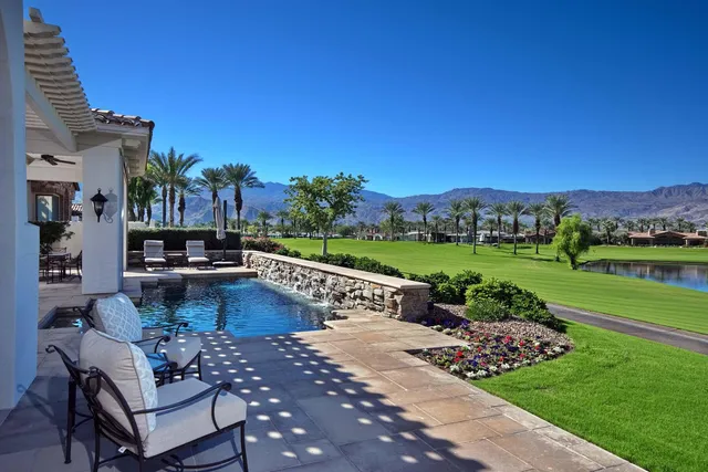 a view of a swimming pool and lounge chairs in back yard of the house