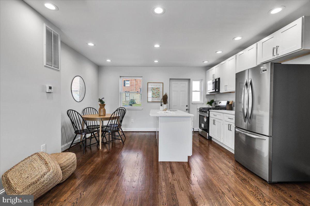 3908 Rokeby Road Baltimore, MD 21229 - Photo 5 of 28 a kitchen with stainless steel appliances granite countertop a refrigerator a microwave oven a dining table and chairs with wooden floor