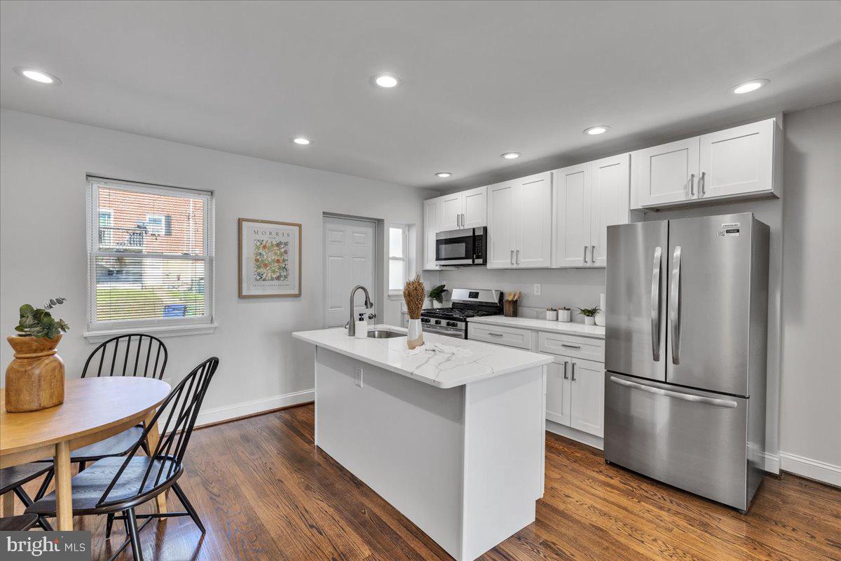 3908 Rokeby Road Baltimore, MD 21229 - Photo 6 of 28 a kitchen with stainless steel appliances a refrigerator a stove a dining table and chairs