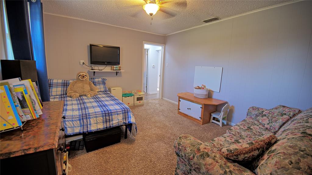 522 Montague Street Nocona, TX 76255 - Photo 6 of 25 a bedroom with bed a flat tv screen and a chandelier