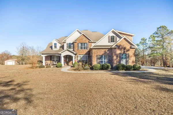 a view of a white house with a big yard and large trees