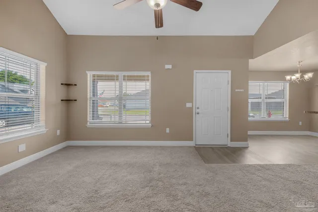 an empty room with windows and chandelier fan