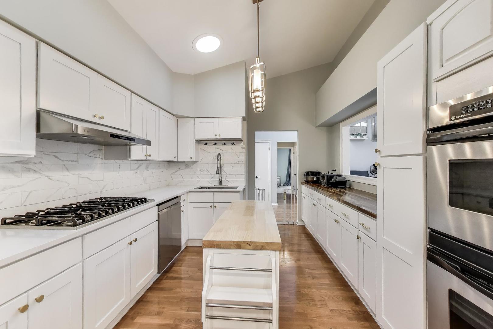 1344 Southwind Drive Northbrook, IL 60062 - Photo 10 of 39 a large white kitchen with stainless steel appliances granite countertop lots of white cabinets a stove and a sink