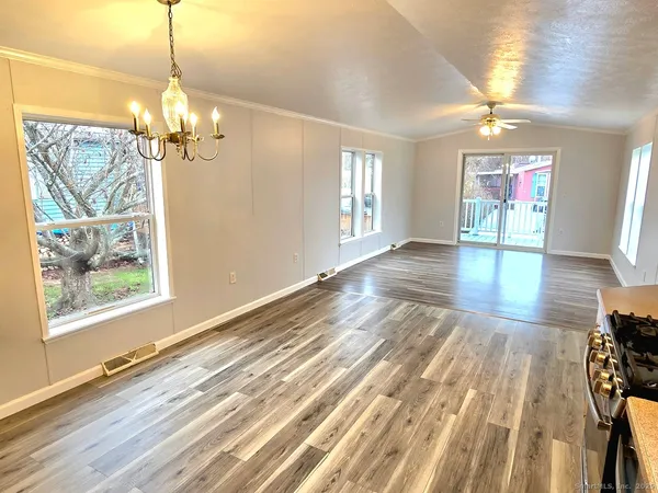 a view of a room with wooden floor chandelier and windows