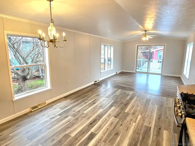 a view of a room with wooden floor chandelier and windows
