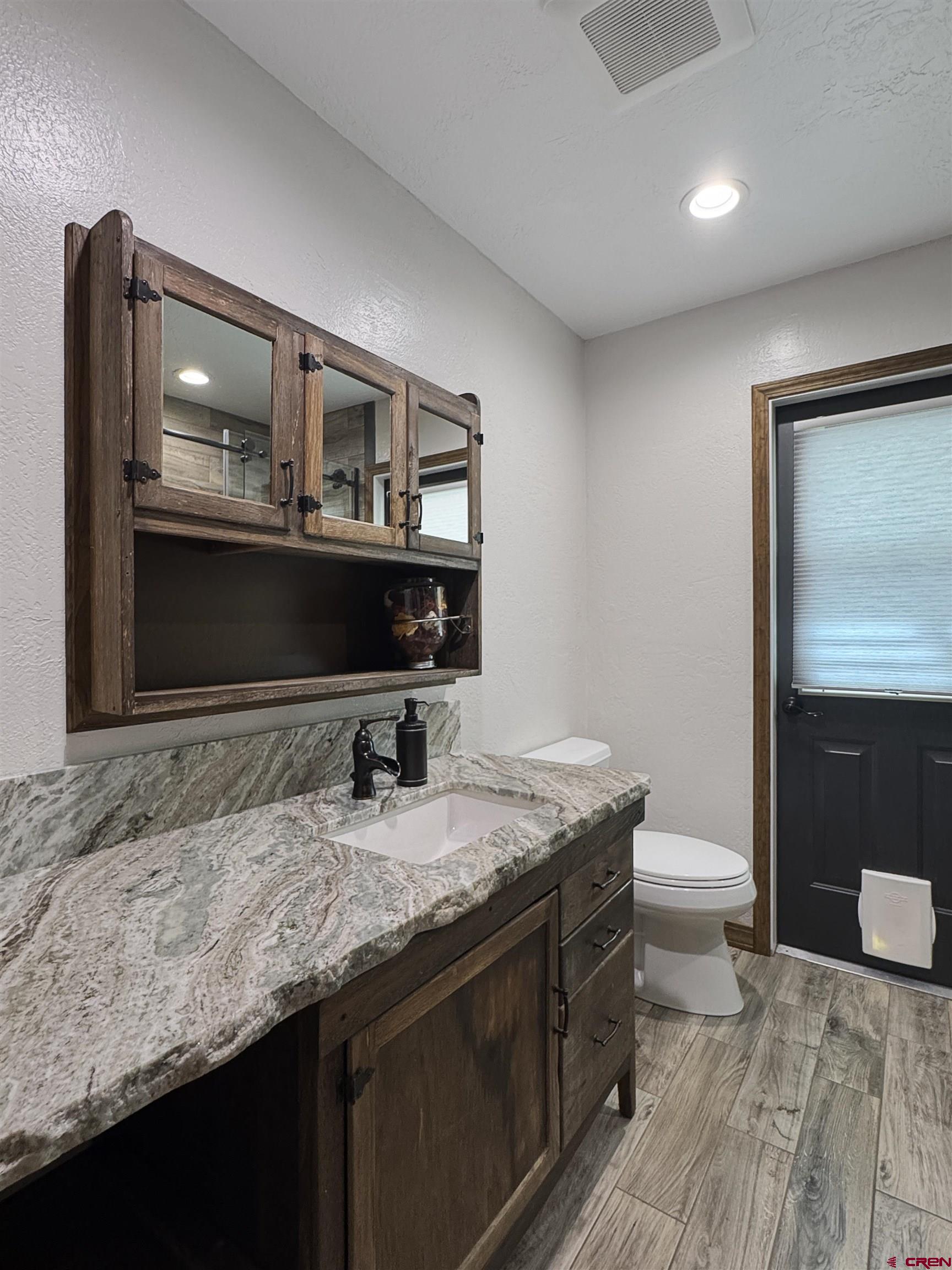 219 Edith Street Cortez, CO 81321 - Photo 17 of 29 a bathroom with a granite countertop sink a toilet and a mirror