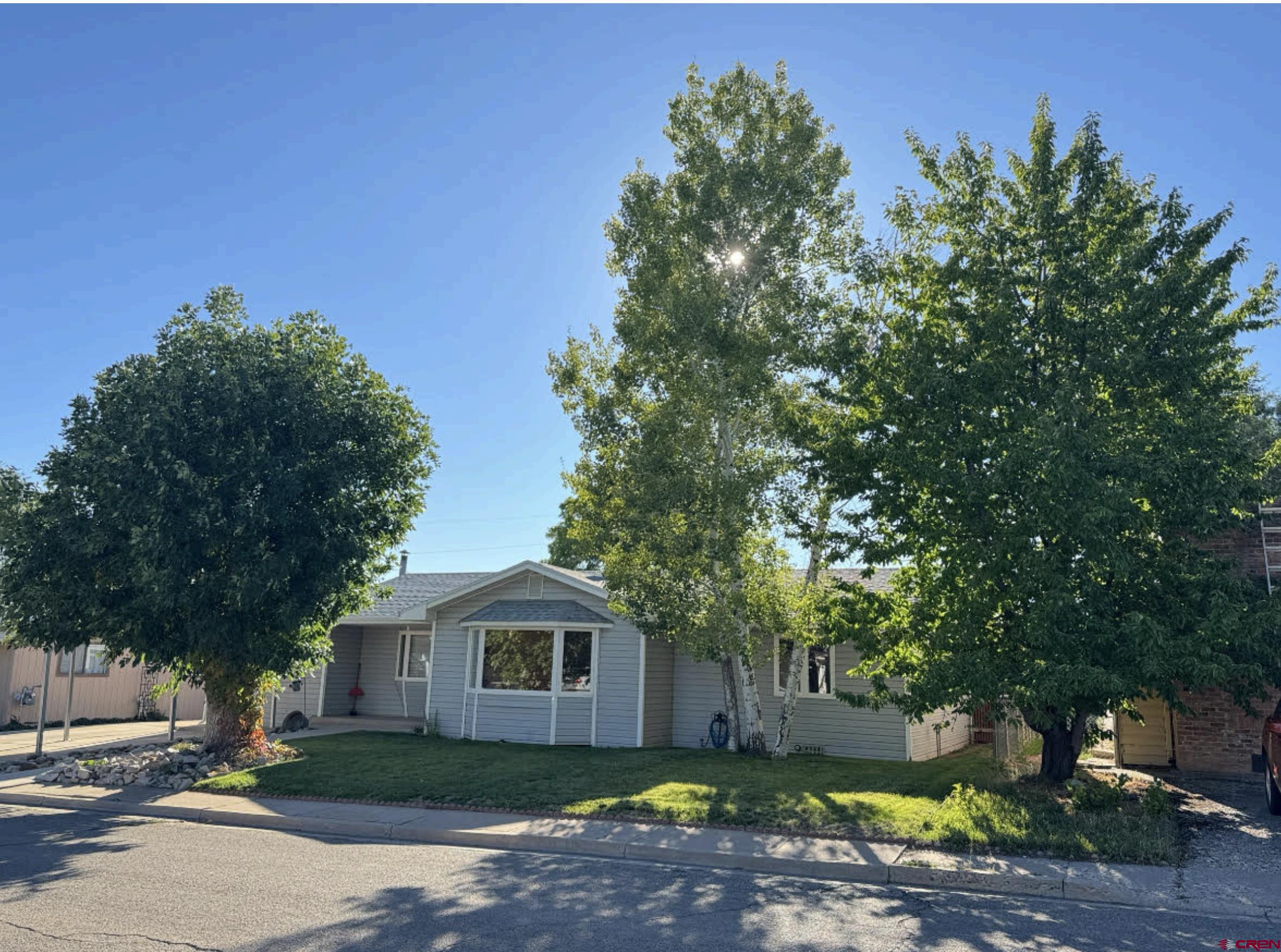 219 Edith Street Cortez, CO 81321 - Photo 2 of 29 a view of a yard with plants and a large tree