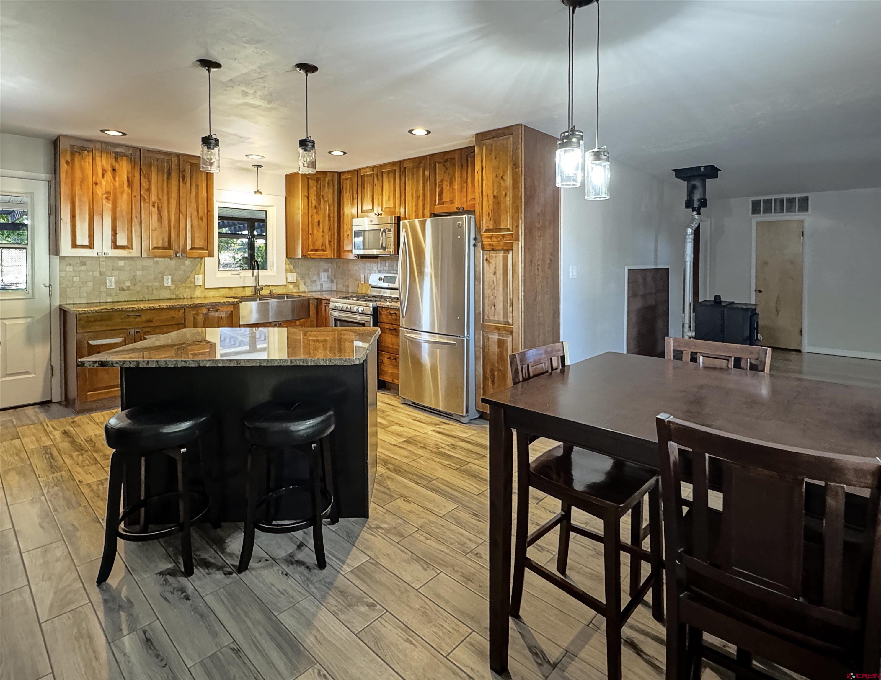 219 Edith Street Cortez, CO 81321 - Photo 9 of 29 a kitchen with stainless steel appliances granite countertop a kitchen island hardwood floor sink stove dining table and chairs
