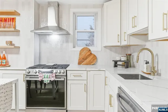 a kitchen with stainless steel appliances granite countertop a stove a refrigerator and a white cabinets