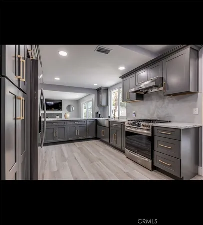 a kitchen with stainless steel appliances kitchen island granite countertop a refrigerator oven a sink and dishwasher