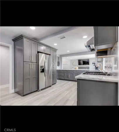 a view of kitchen with stainless steel appliances kitchen island granite countertop a refrigerator oven a sink with wooden cabinets