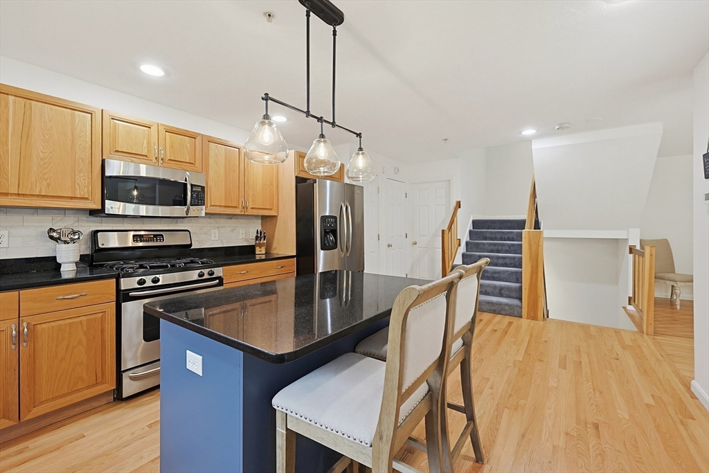3002 Maple Brook Road, Unit 3002 Bellingham, MA 02019 - Photo 16 of 42 a kitchen with stainless steel appliances granite countertop a refrigerator a stove top oven a sink dishwasher and white cabinets with wooden floor