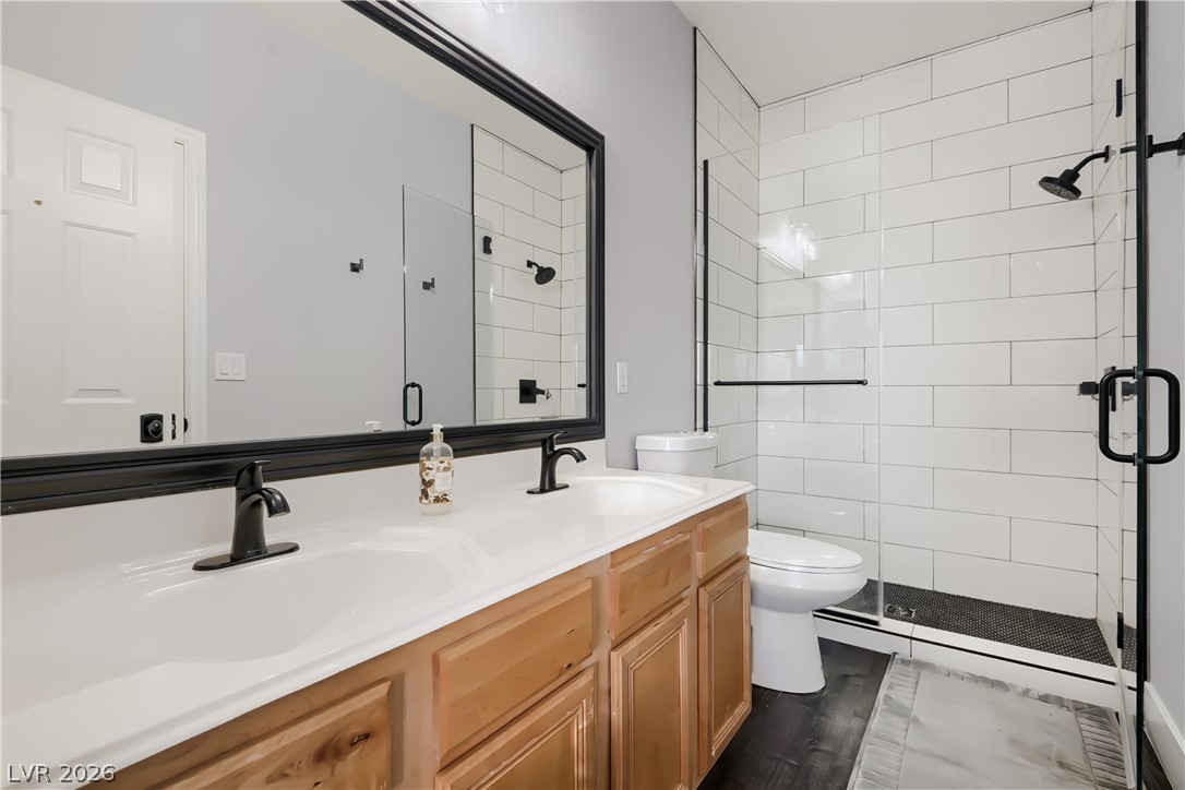 251 Integrity Ridge Drive Henderson, NV 89052 - Photo 21 of 28 A sleek modern bathroom featuring a double vanity, black fixtures, and a spacious glass-enclosed shower.