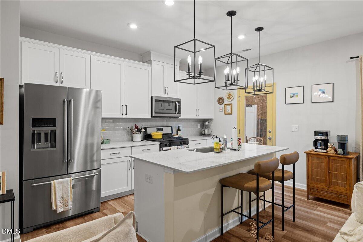 845 Oak Center Drive Raleigh, NC 27610 - Photo 7 of 29 a kitchen with stainless steel appliances a white center island a refrigerator a stove a kitchen island a dining table and chairs