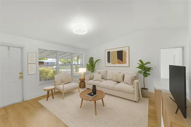 a living room with furniture a flat screen tv and a potted plant