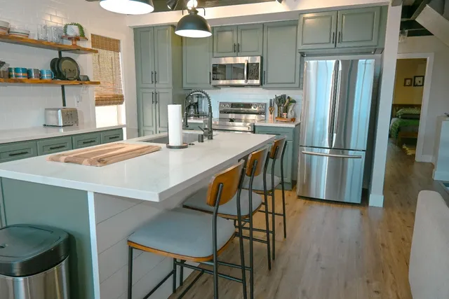 a kitchen with stainless steel appliances granite countertop a refrigerator a sink and wooden cabinets