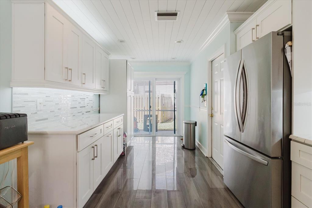 11521 Rose Tree Drive New Port Richey, FL 34654 - Photo 7 of 37 a kitchen with granite countertop a refrigerator a sink and white cabinets